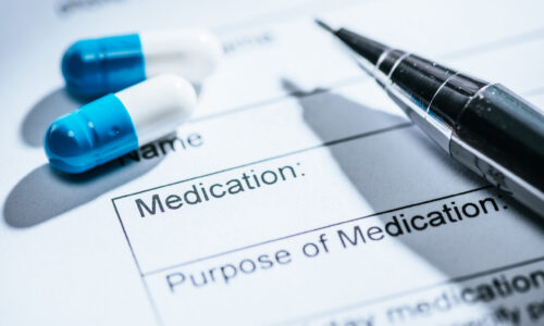 close up view of medical questionnaire, blue pills and on table